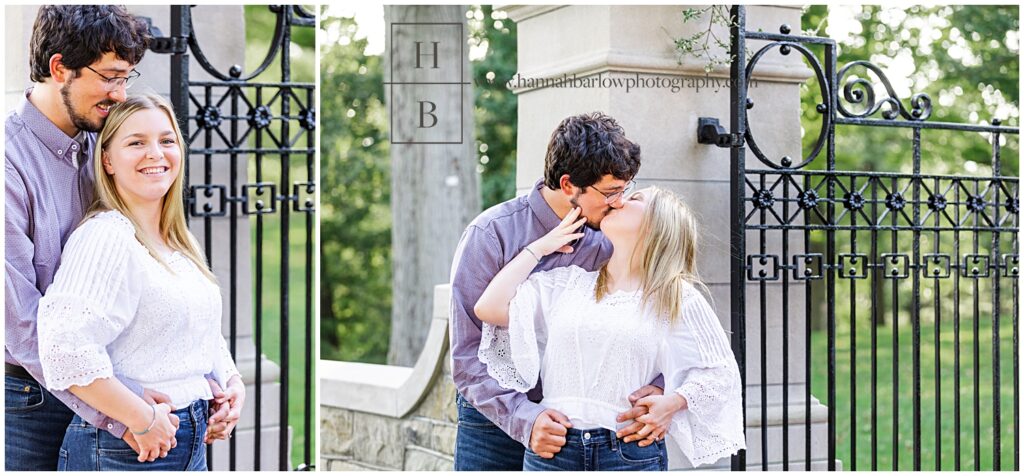 Couple posing and kissing by stone wall and black iron gate.