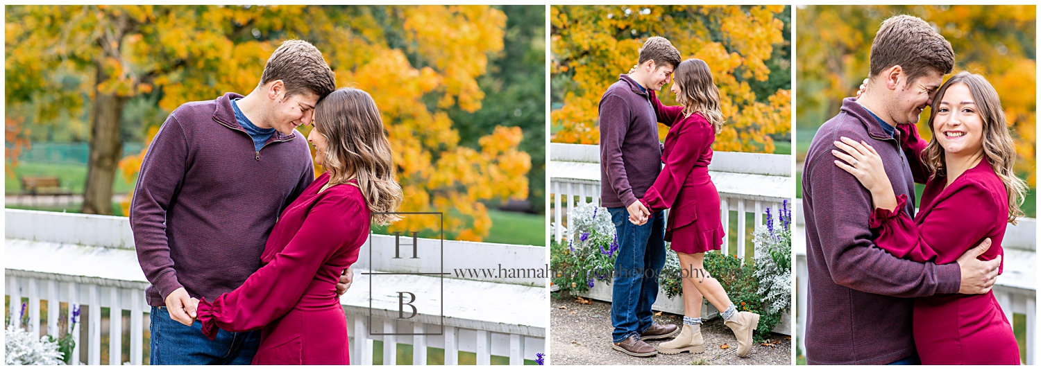Engagement Photos of Couple Standing by White Fence in Front of Fall Tree