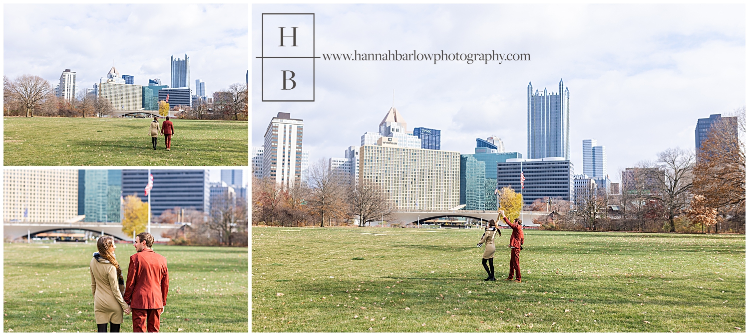Man in red suit walking with his fiance in PIttsburgh with city skyline.