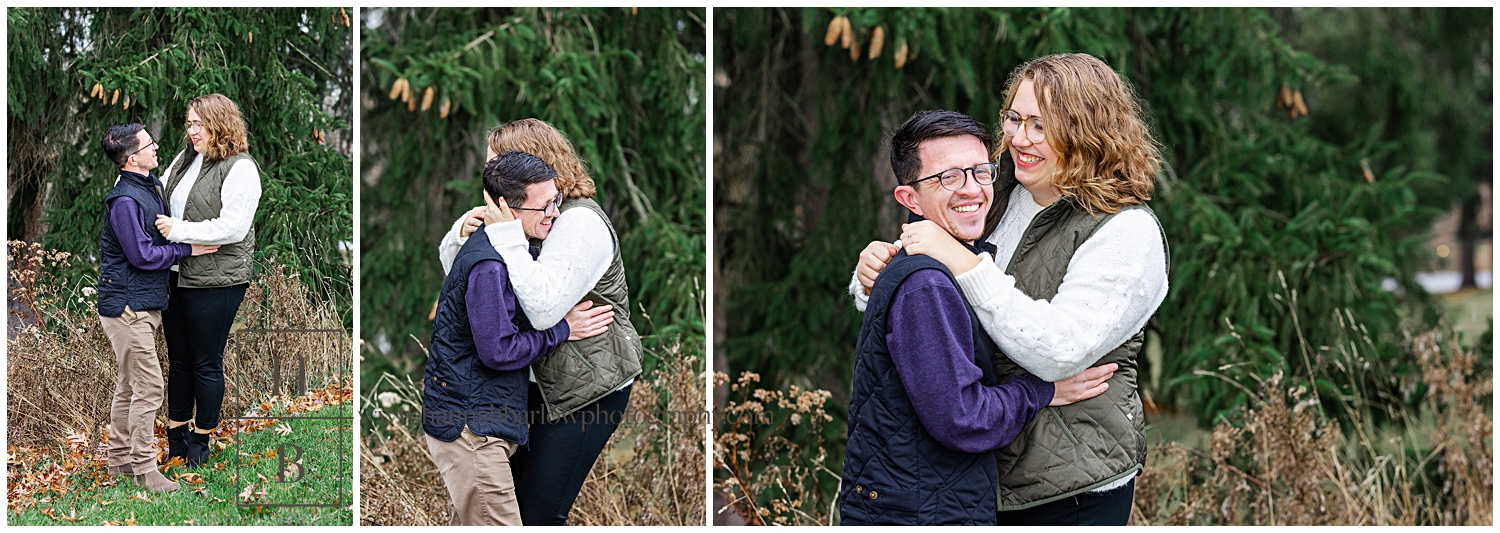 Couple embraces and laughs for engagement photos by pine trees