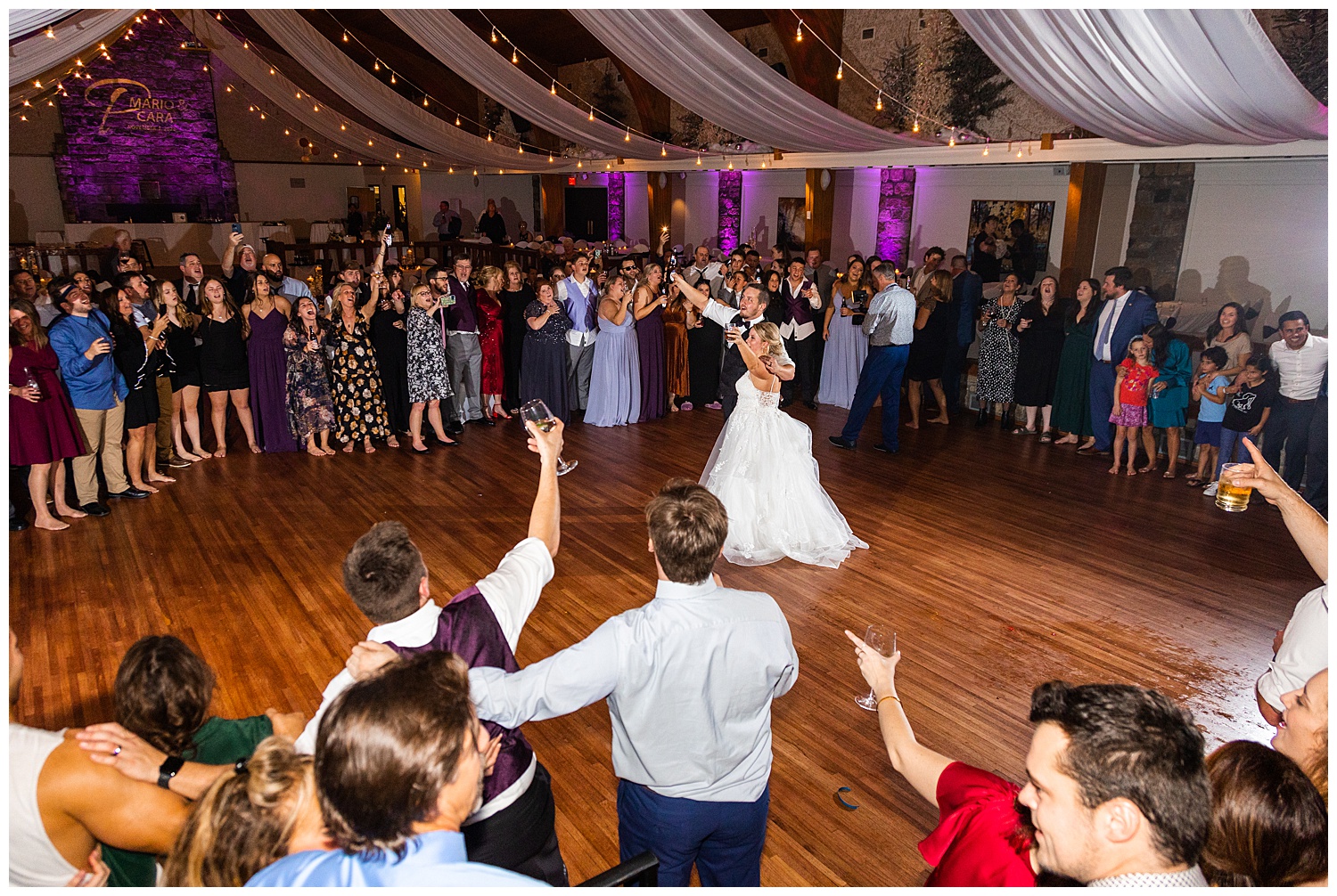 Couple stands in circle of wedding reception guests on dance floor