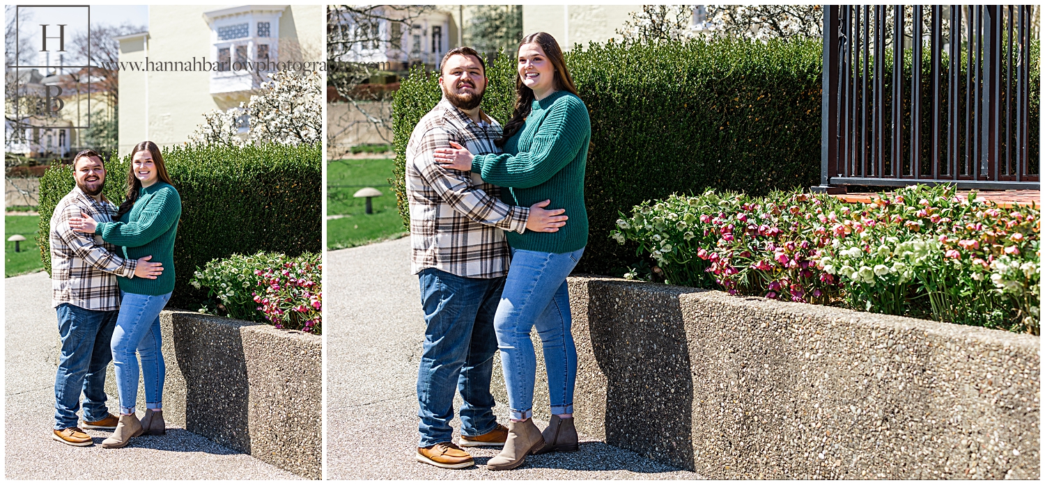Couple posing by concrete flower bed full of spring flowers