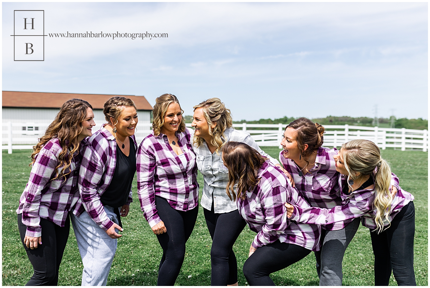 Bride and bridesmaids in grey and purple flannel hug and laugh.