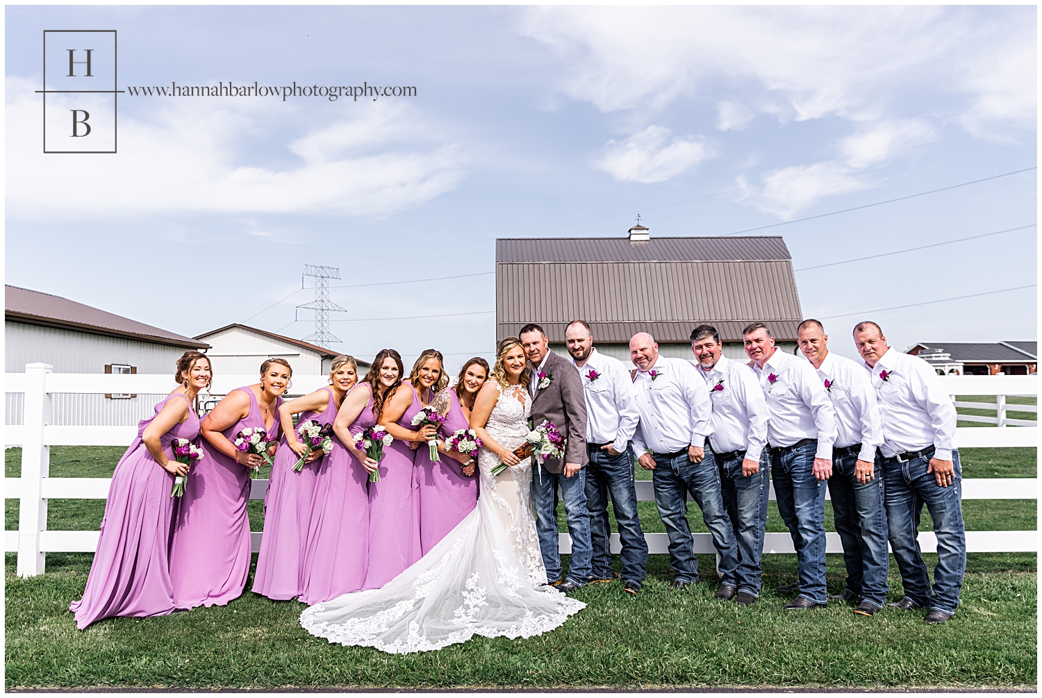 Full bridal party poses and hugs in on couple with purple dresses and men in jeans.