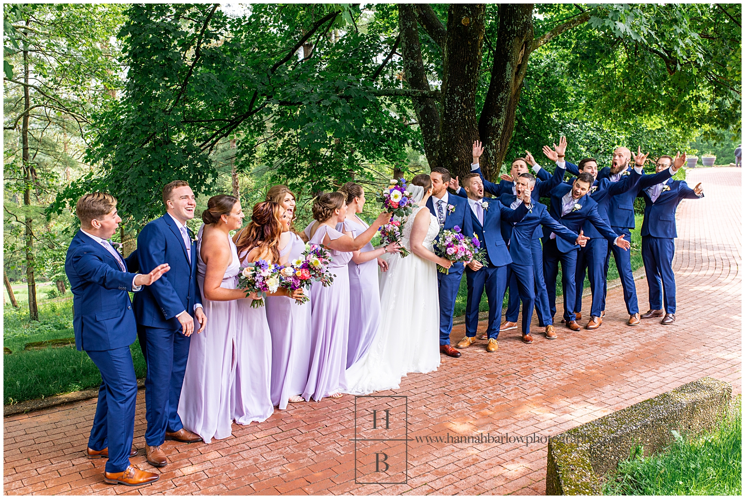 Bridal party cheers as bride and groom kiss.