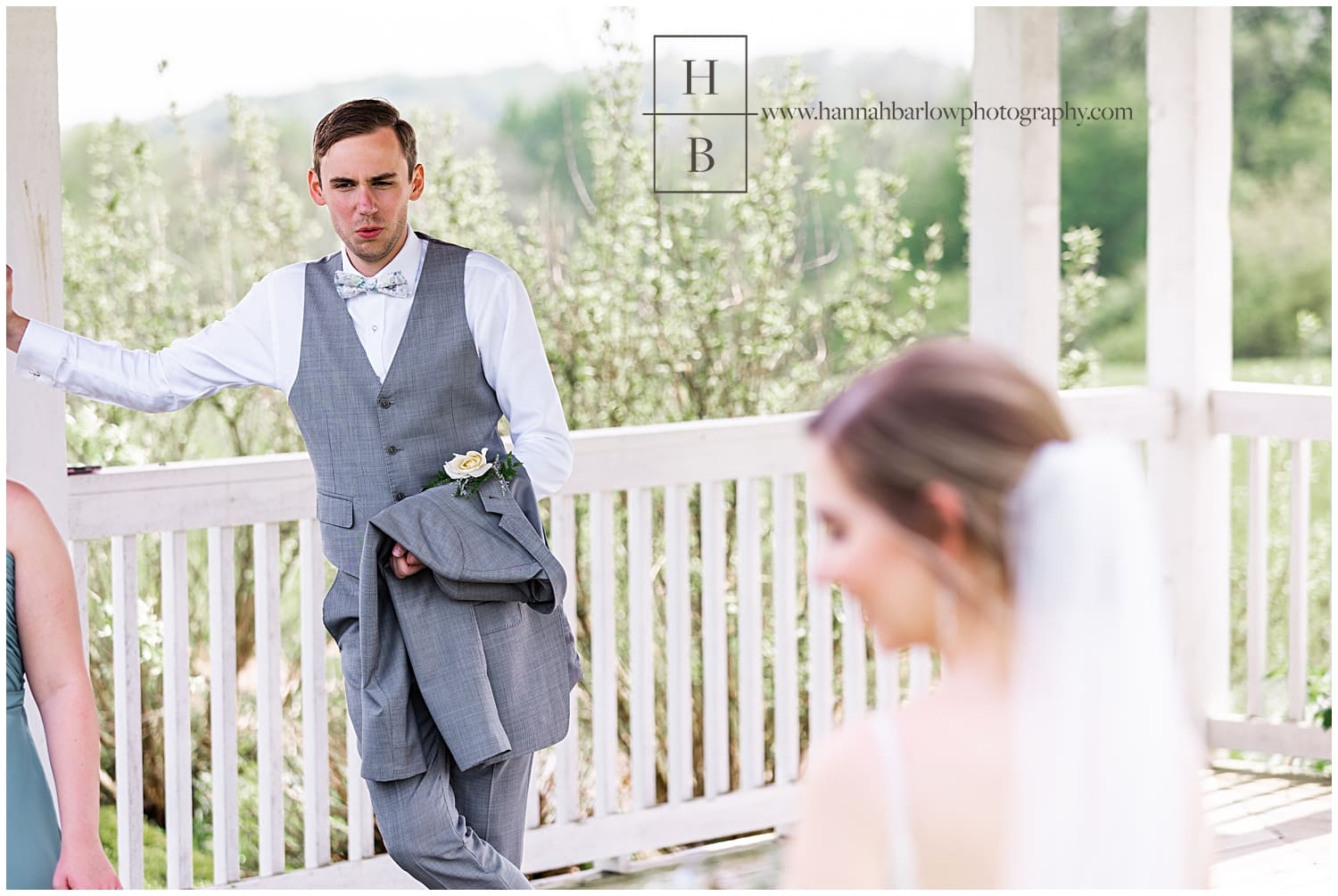 Groom stands off to the side and admires bride
