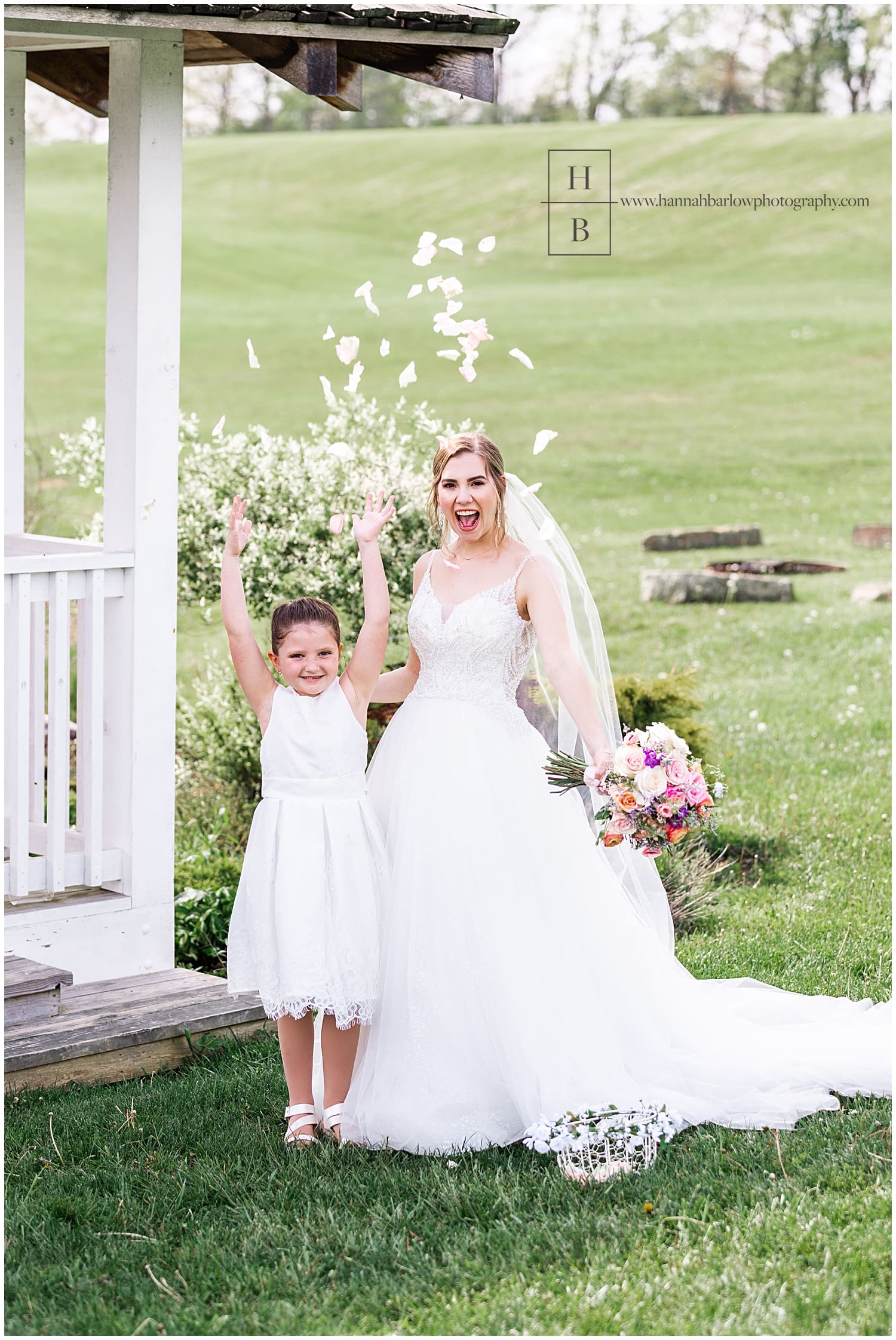 Flower girl throws rose petals while posing with bride
