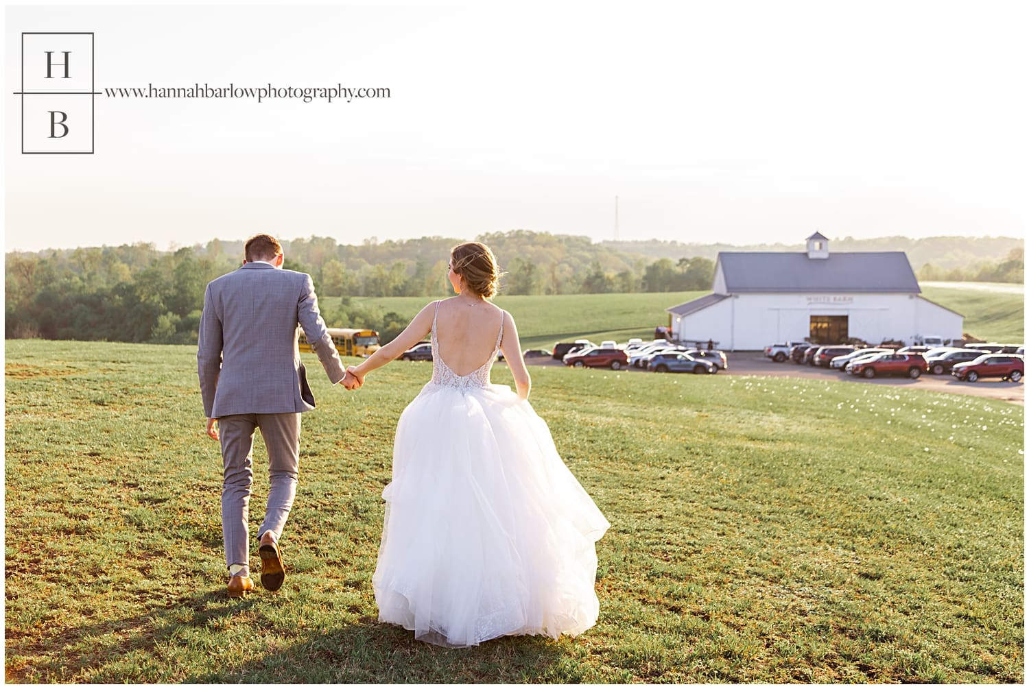 Bride and groom walk hand in hand during golden hour with white barn in prospect pa in background