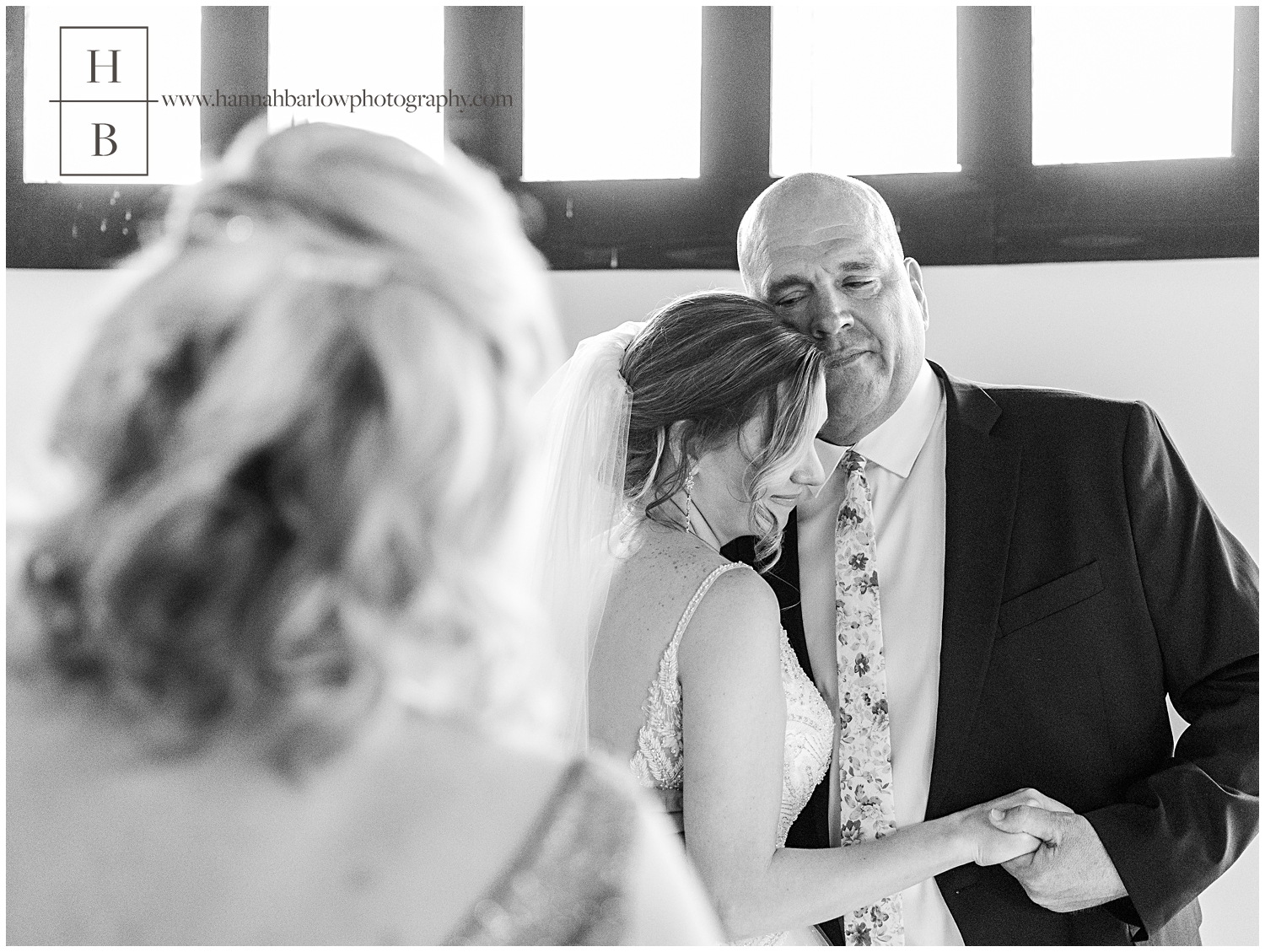 Dad embracing daughter on wedding day with mom standing in foreground.