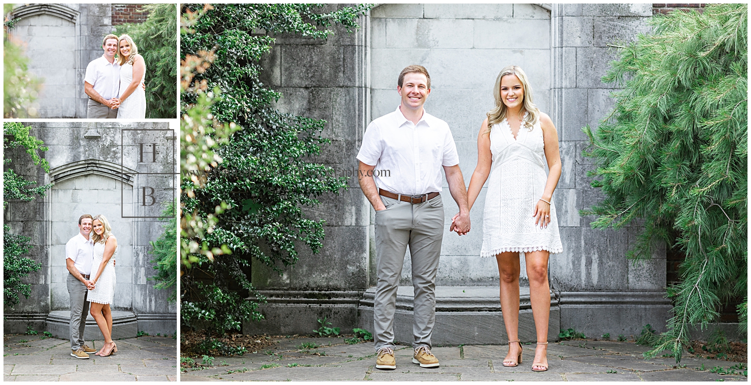 Lady in white dress stands with fiance in white dress shirt holding hands by stone wall.
