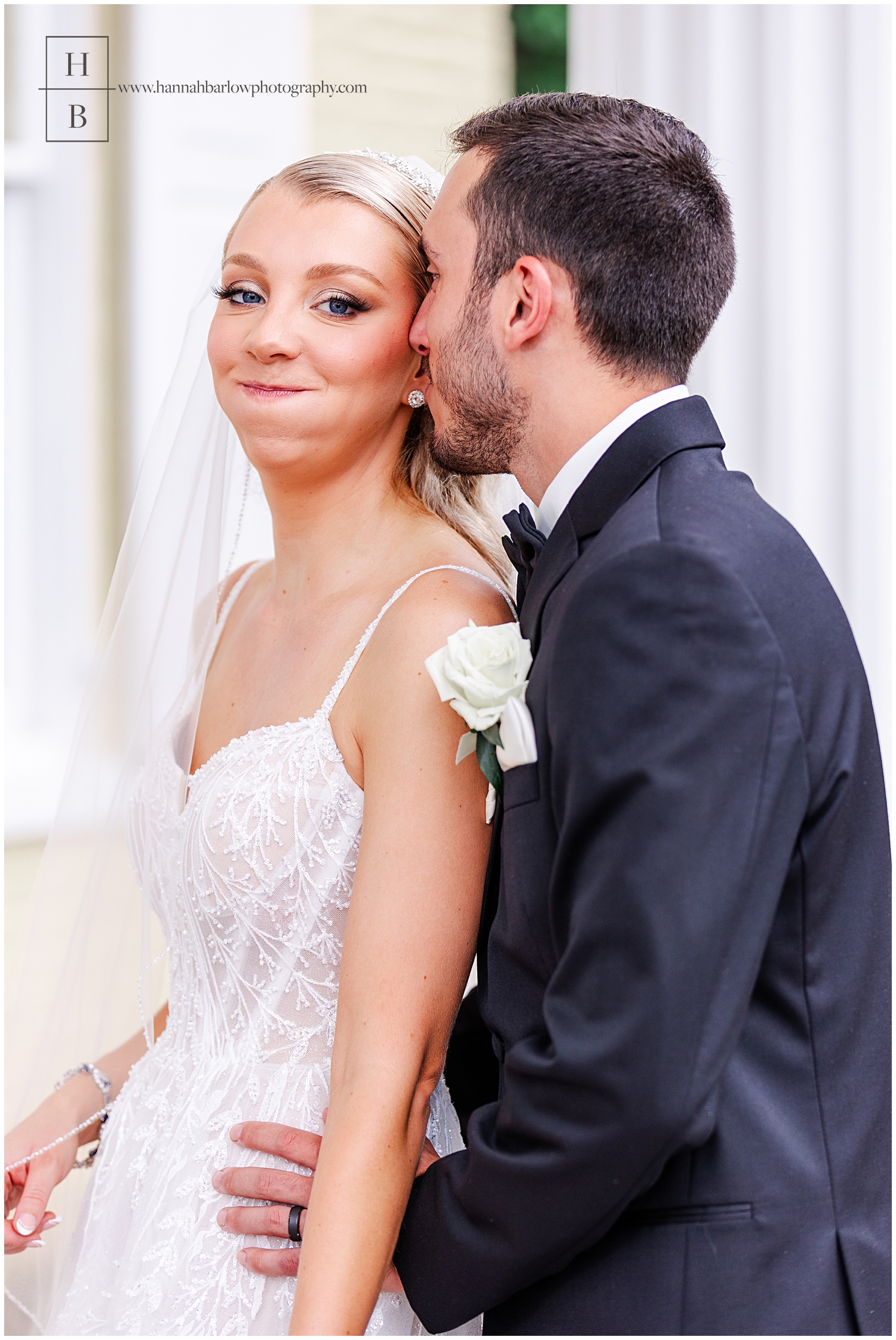 Bride makes funny face puffing out cheeks while groom snuggles with her.