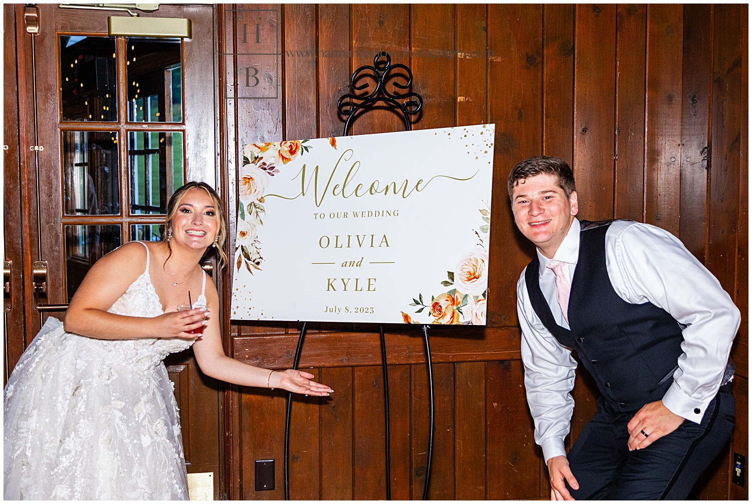 Bride and groom pose showing off wedding sign