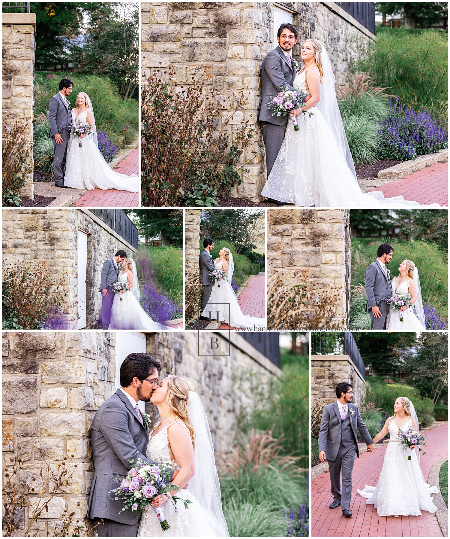 Wedding couple stands by stone wall surrounded by purple flowers.