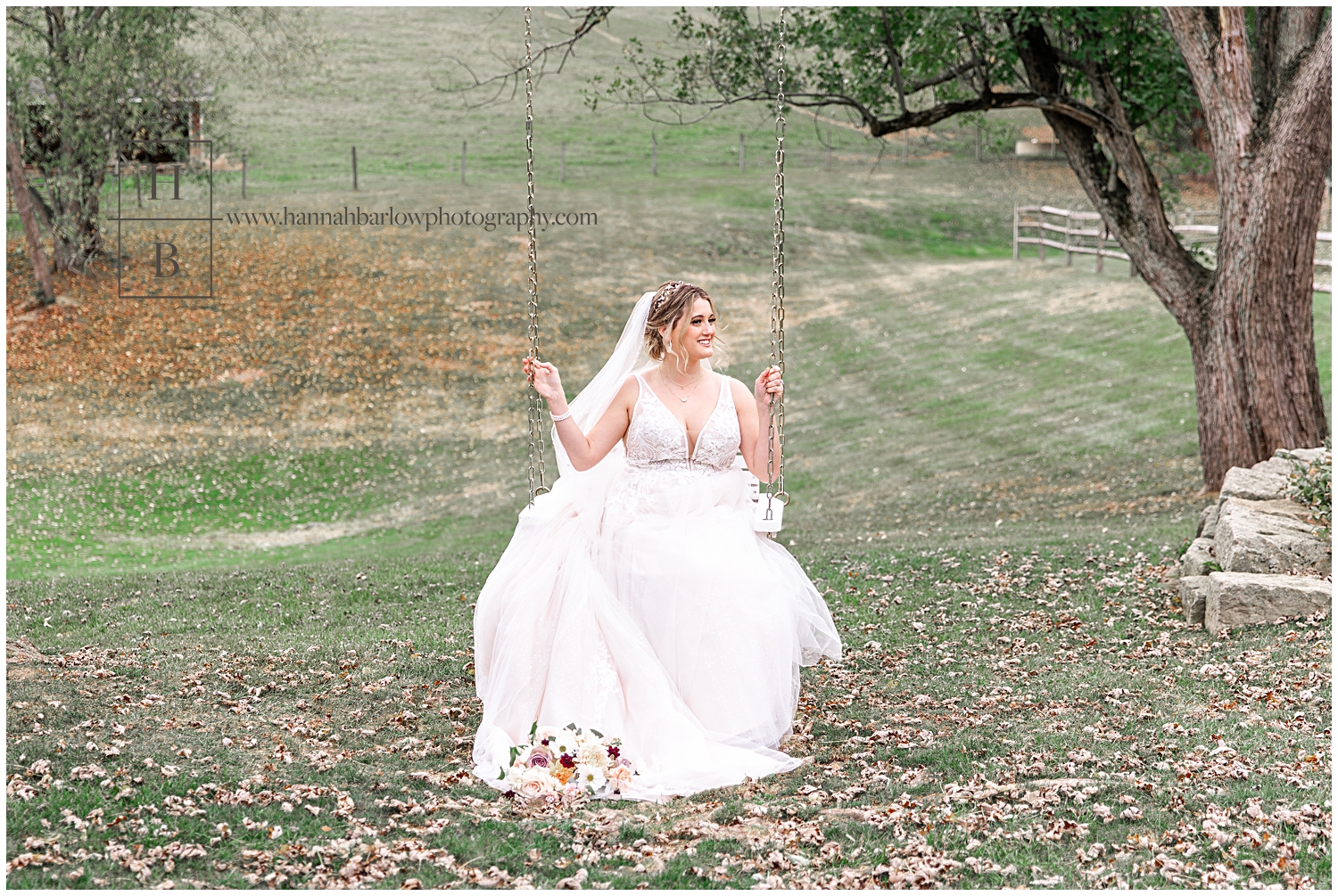 Bride in gown sits on swing and smiles.