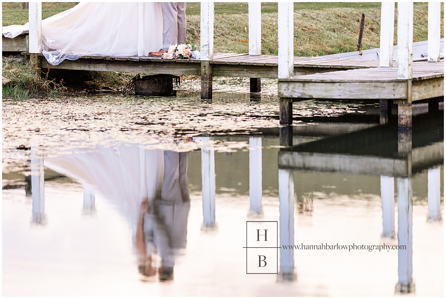 Bride and groom reflection in lake is shown.
