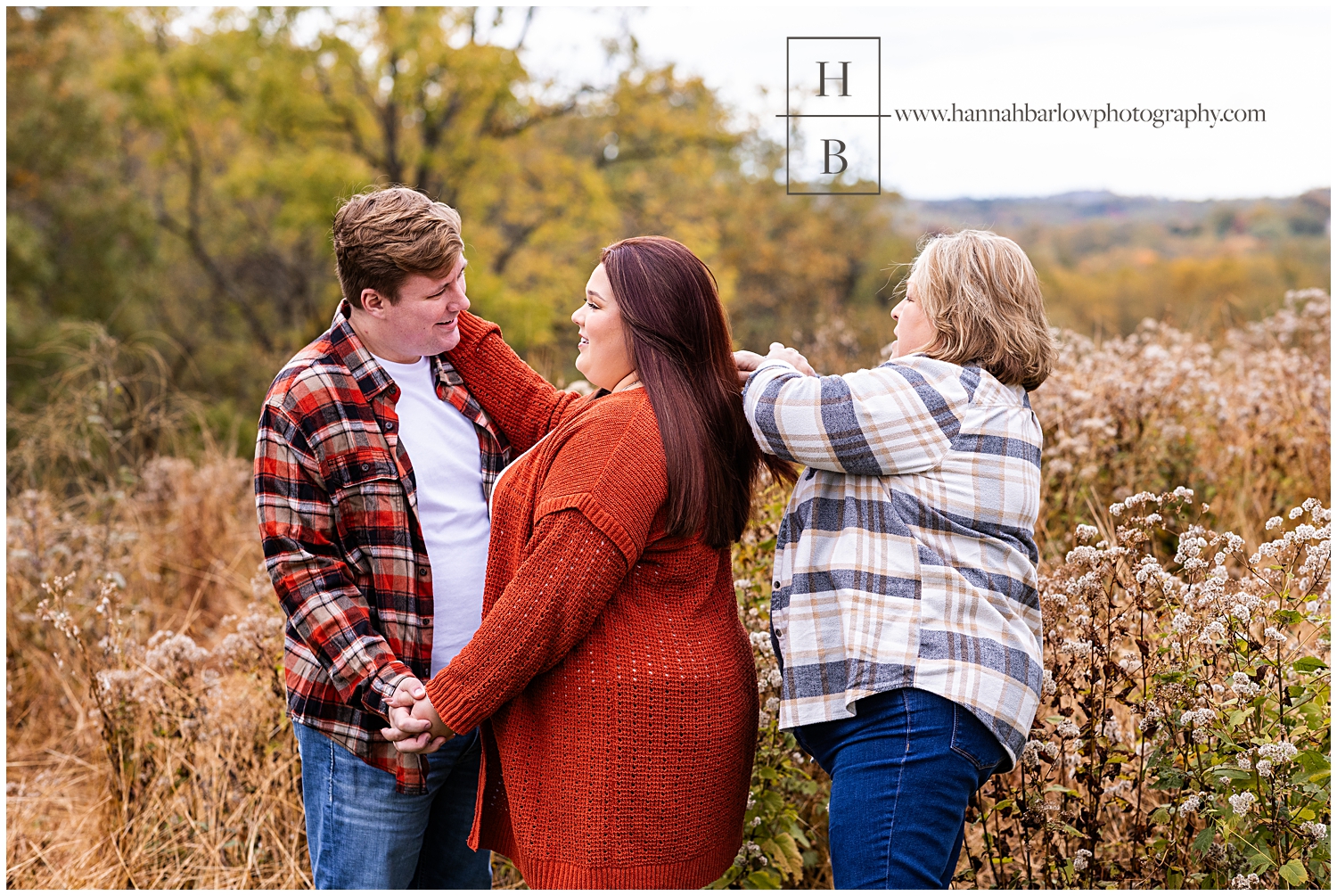 Mom fixes daughters hair for engagement photos in field.