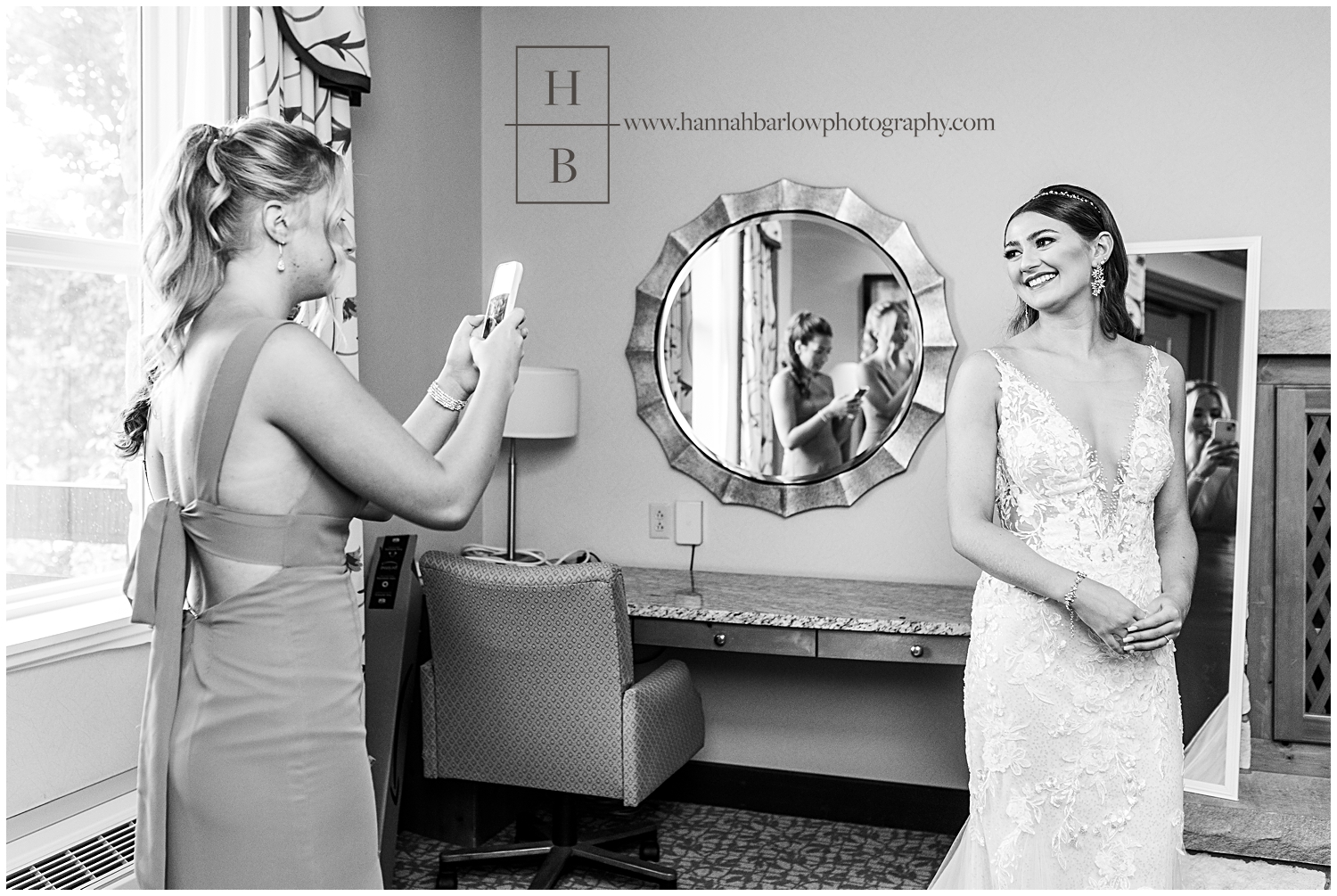 Black and white photo of bridesmaids taking photo of bride with their phone.