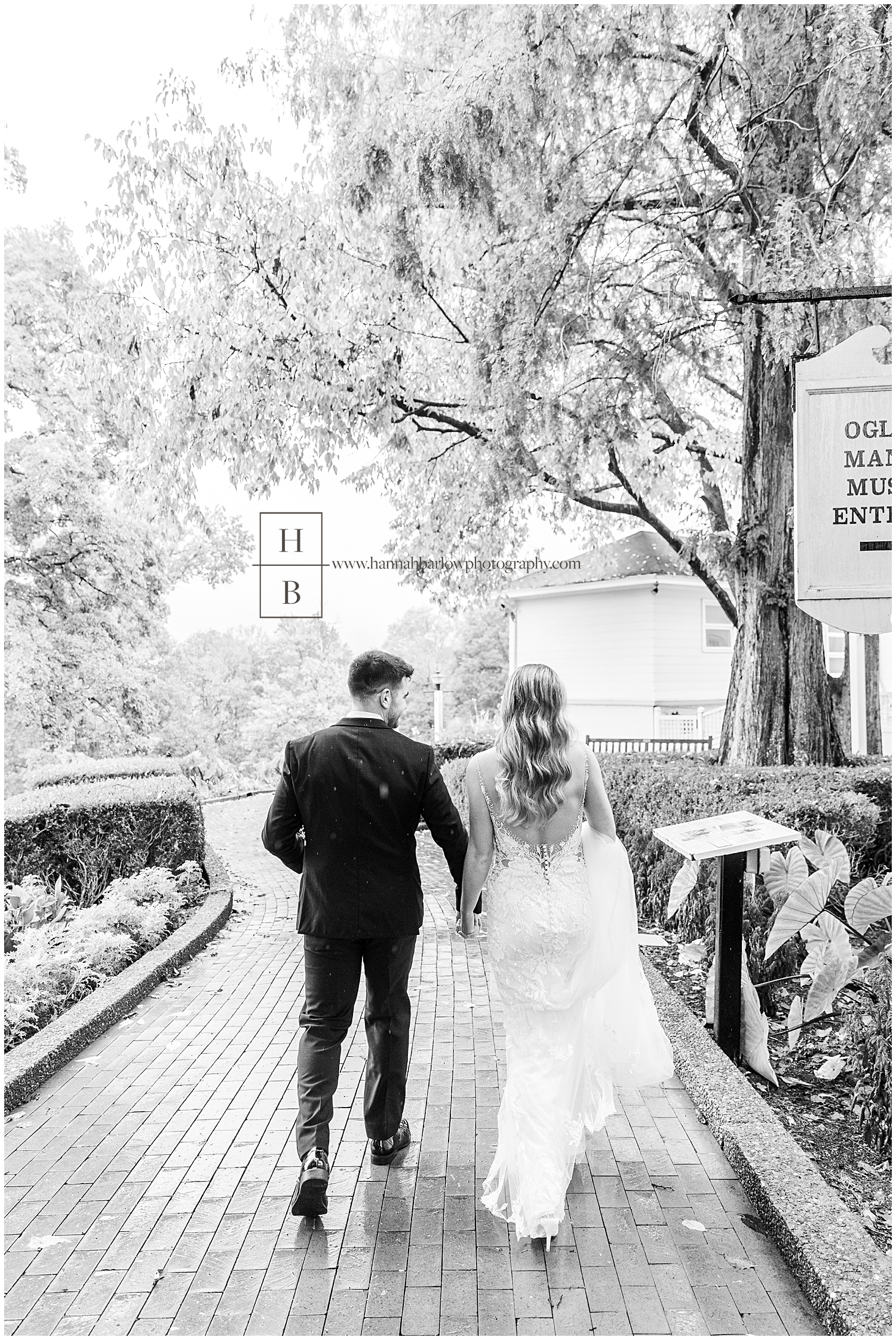 Black and white photo of bride and groom walking away from photographer in rain.