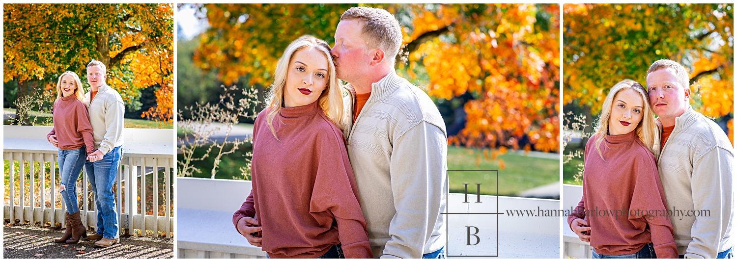 Man embraces woman in peach sweater with fall trees in backgrund.
