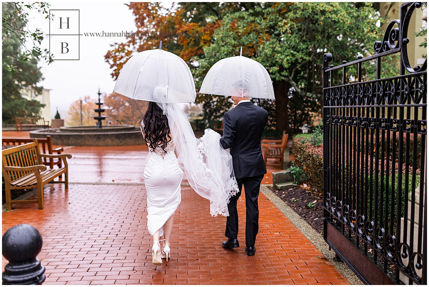 Bride and groom carry umbrellas while walking in the rain