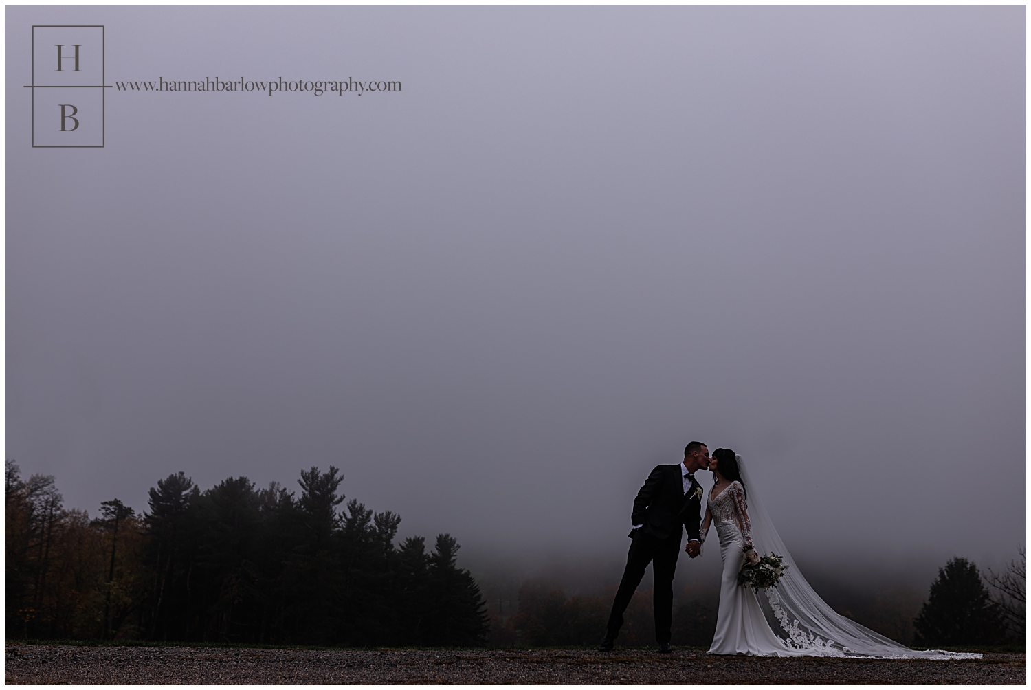 Bride and groom kiss for foggy wedding photo