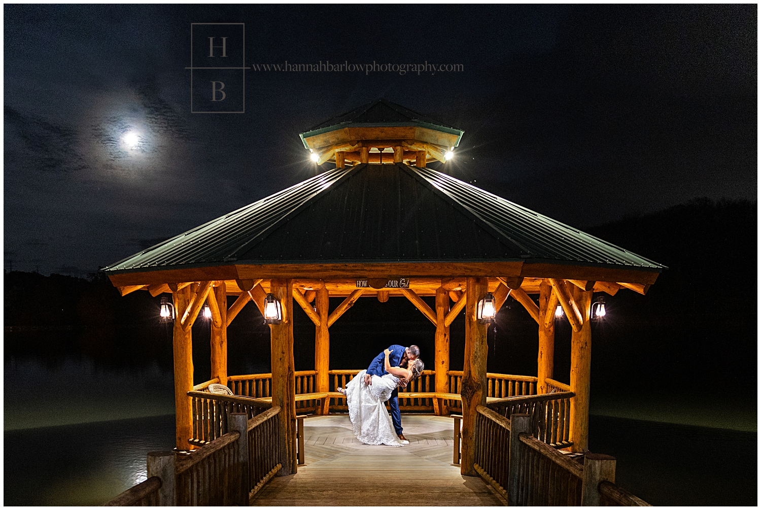 Groom dips bride at night under full moon in gazebo