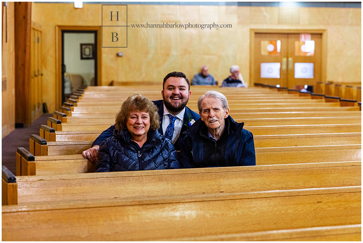 Groom poses with older couple in church.