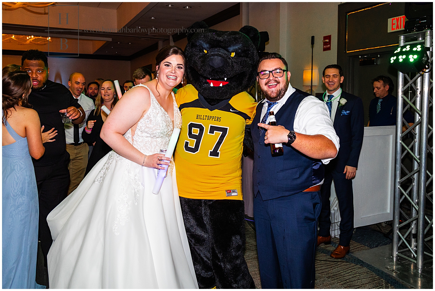 Wedding couples poses with bear mascot at wedding reception