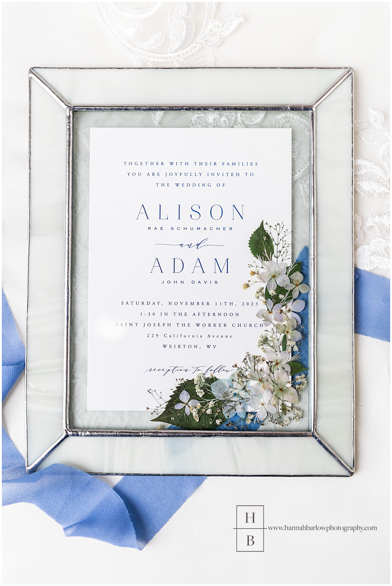 Wedding invitation framed in a white and glass picture frame.