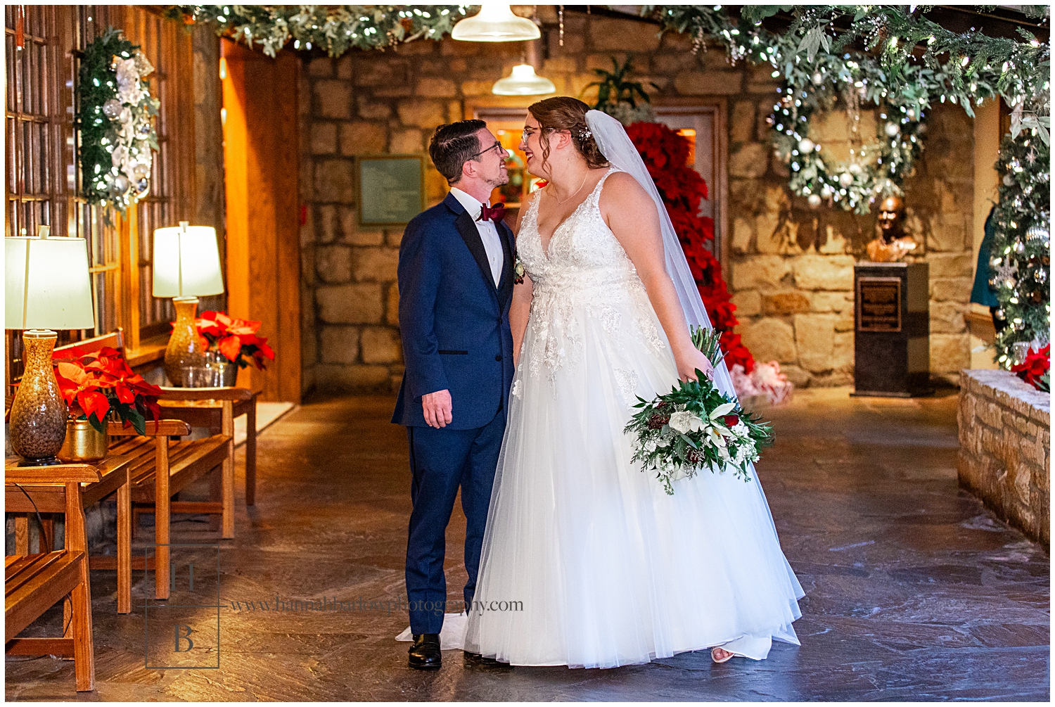 Bride and groom look at one another in stone hallway with holiday decor