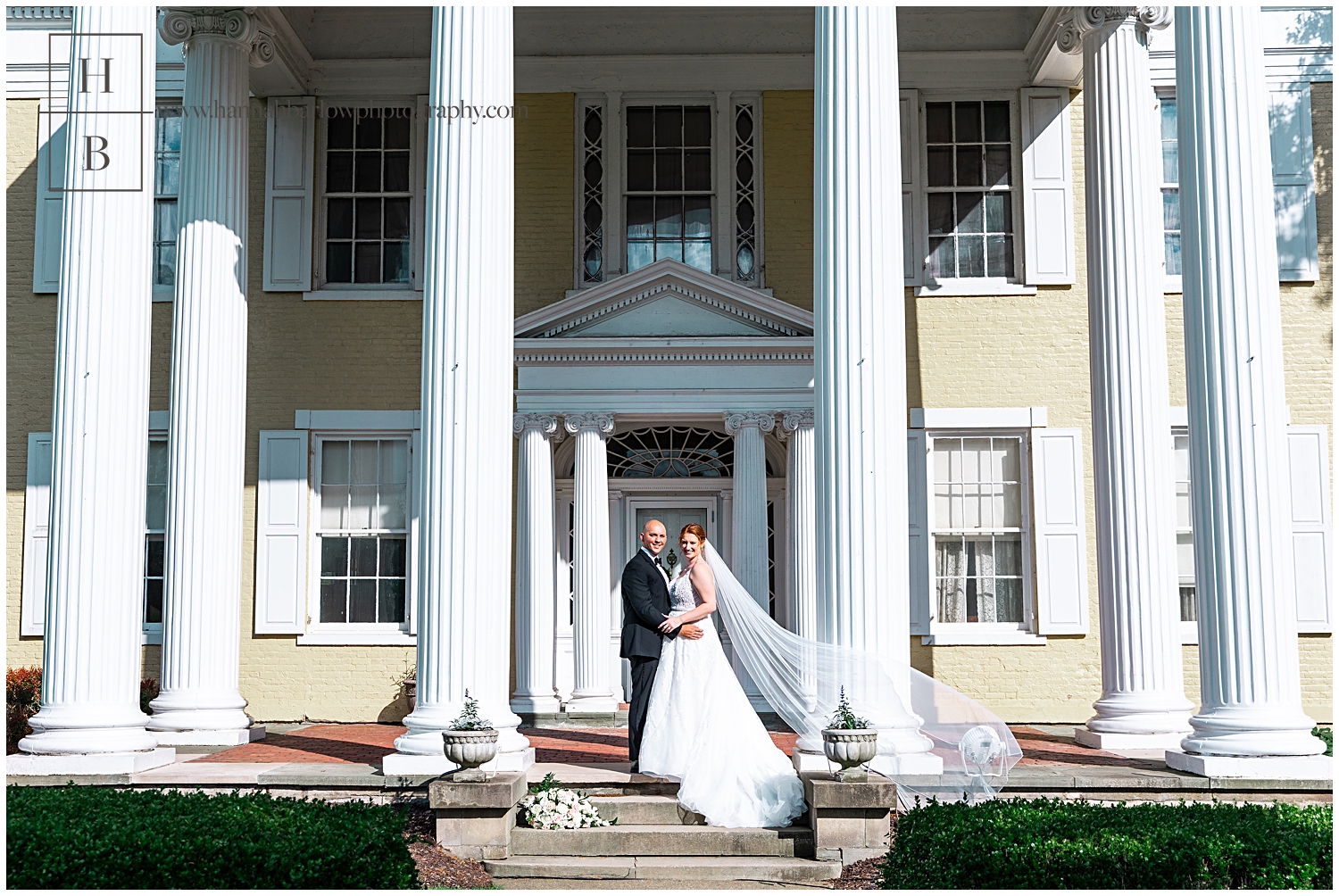 Bride and groom pose in front of yellow mansion