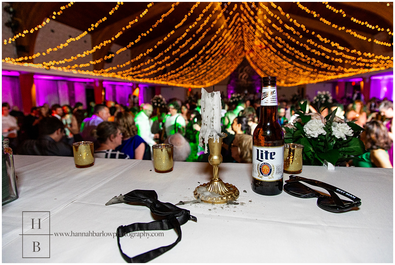 Bowtie, empty beer bottle and burned out candle are highlighted in the foreground of dance floor photo