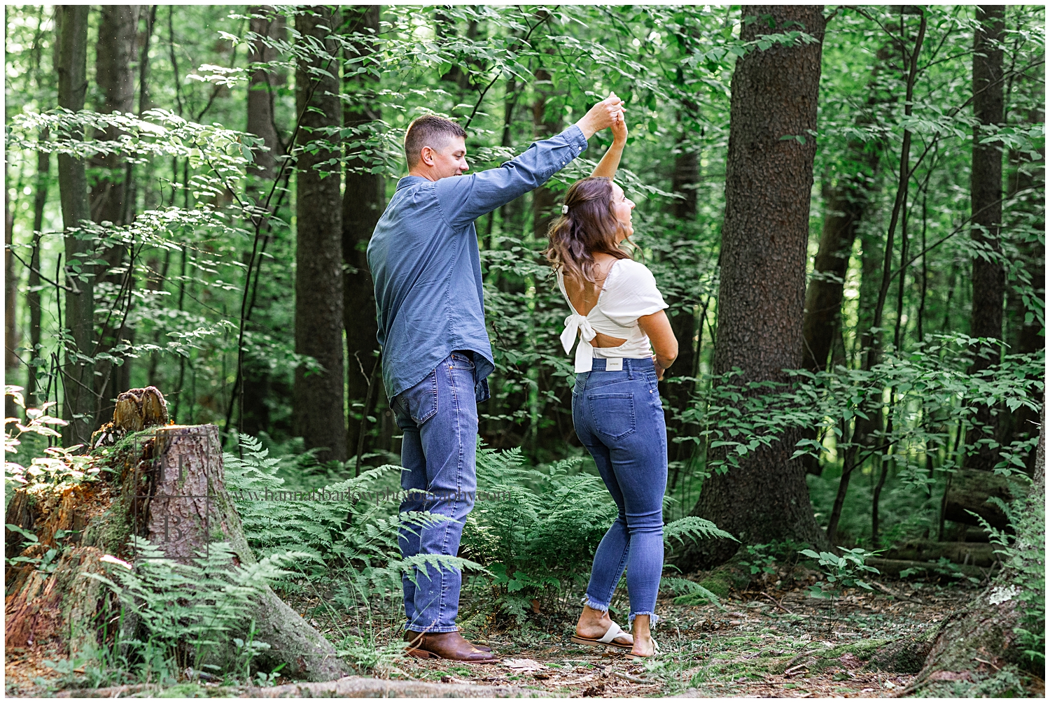 Man spins woman while dancing in forest for engagement photos