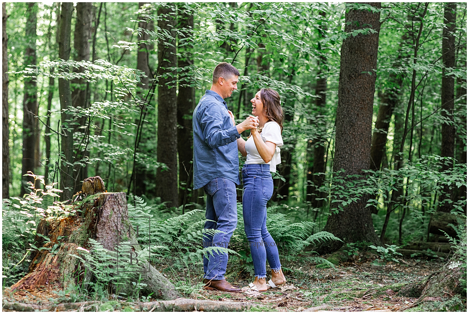 Man and woman pretend to dance for engagement photos in forest