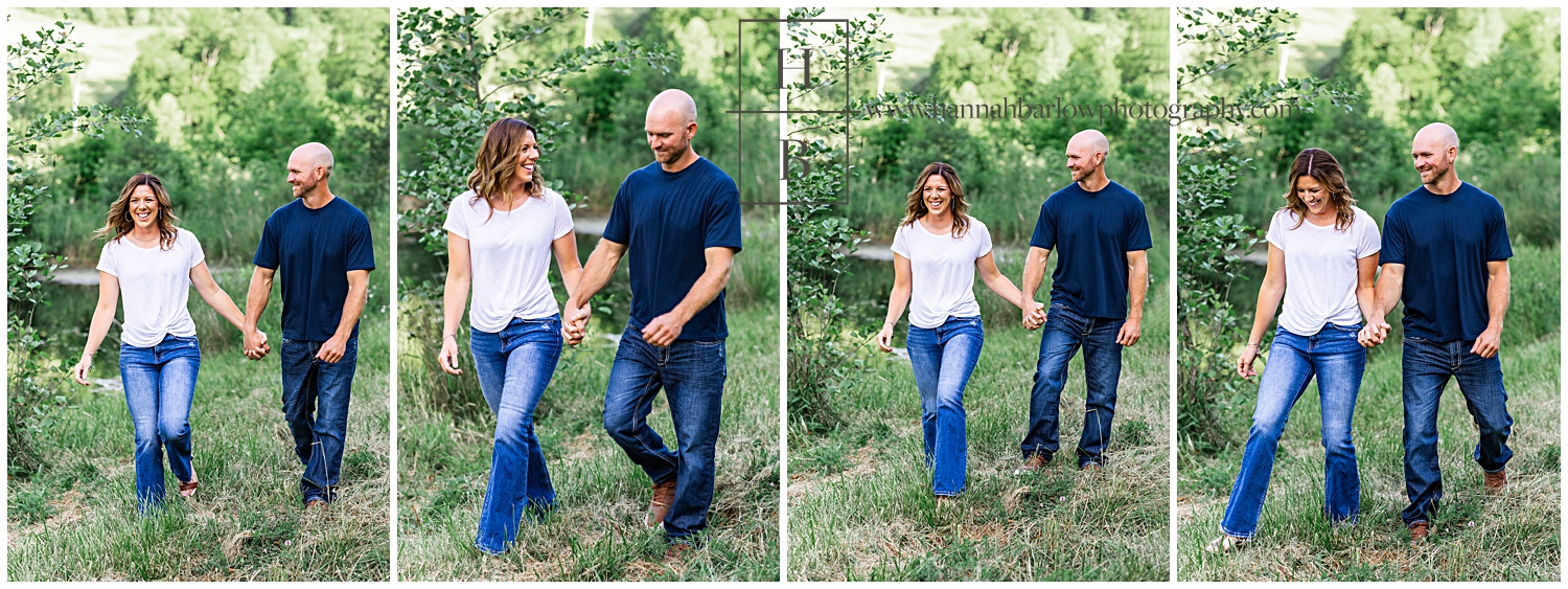 Couple walks and laughs in the country fields by lake for engagement photos