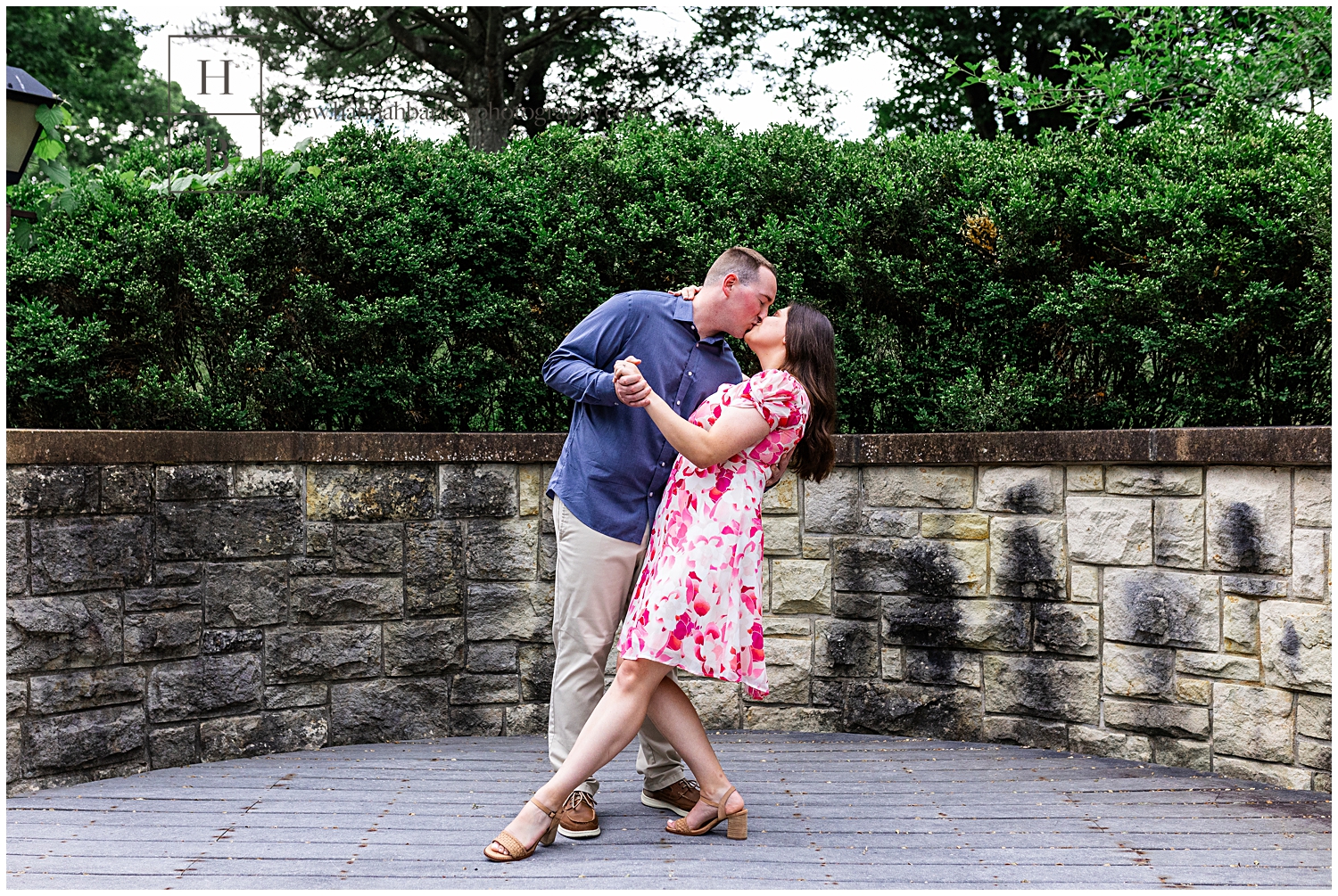 Man dips fiancee in front of stone wall