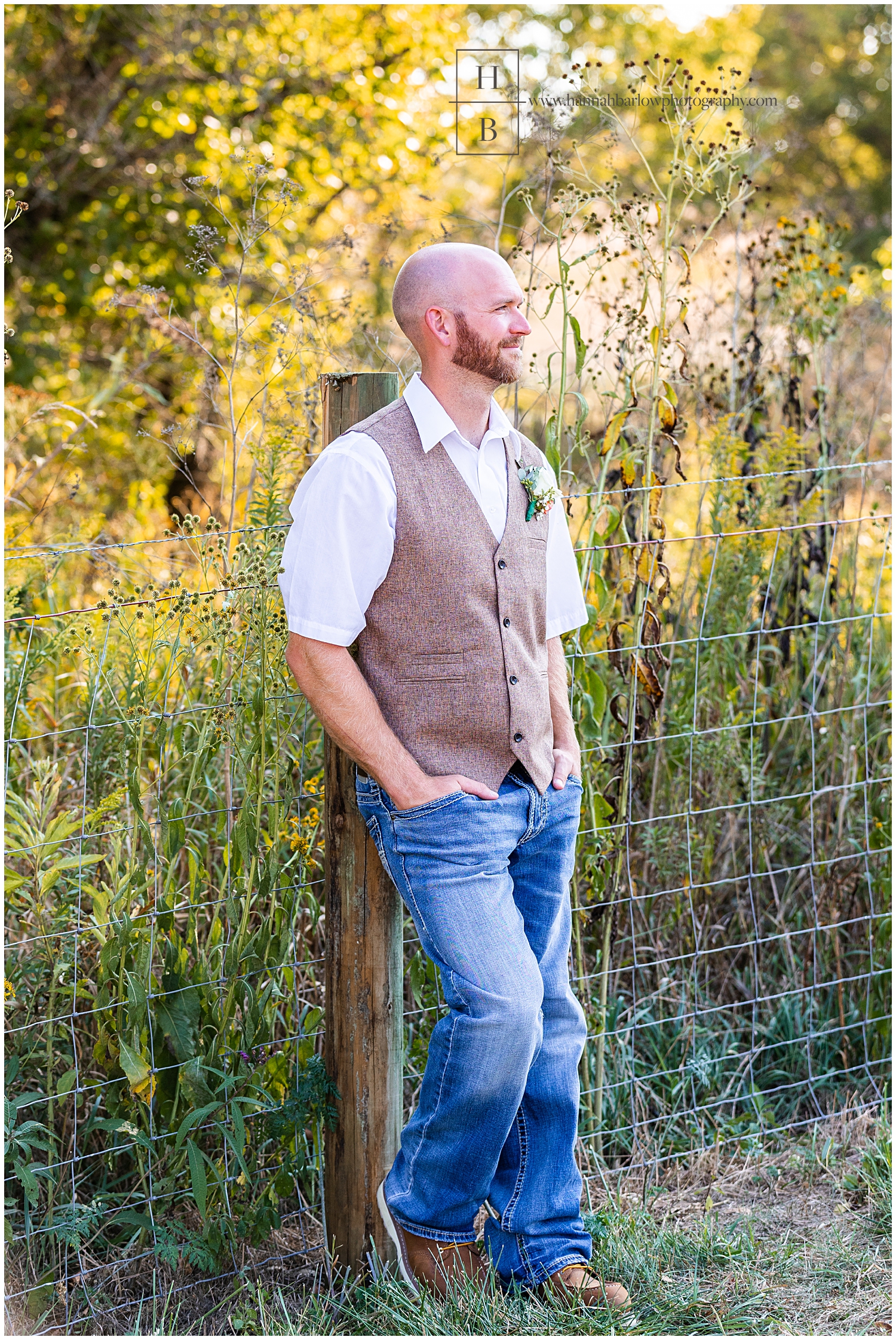 Groom leans on fence post for portrait