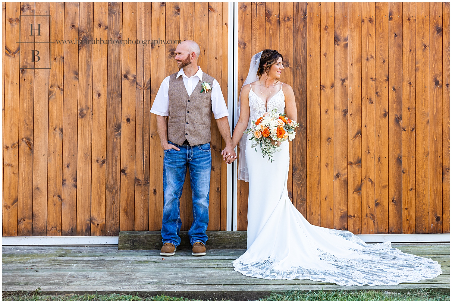 Bride and groom look away from one another posing in front of barn door