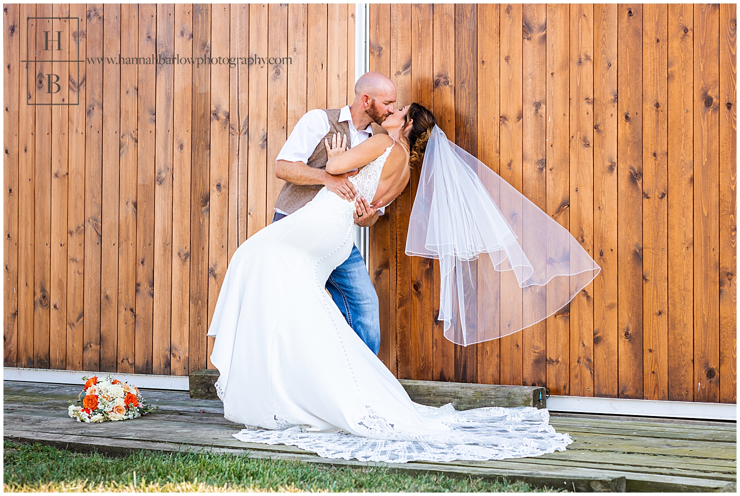 Groom dips bride in front of Barn Door