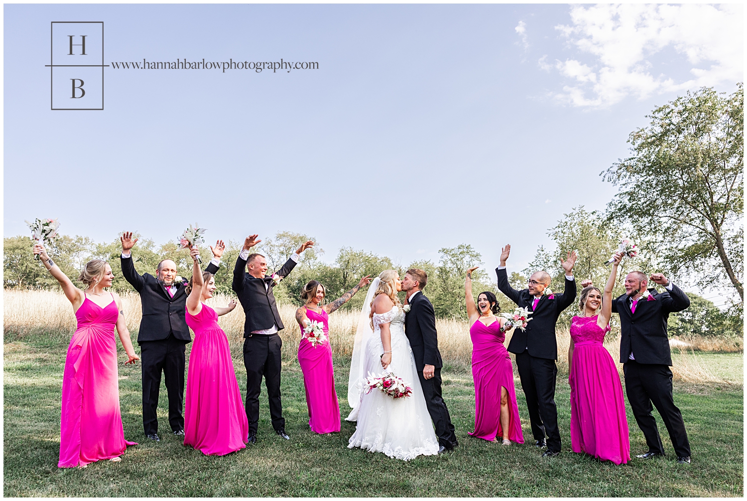 Bridal party and fuchsia pink and black tuxes pose with couple