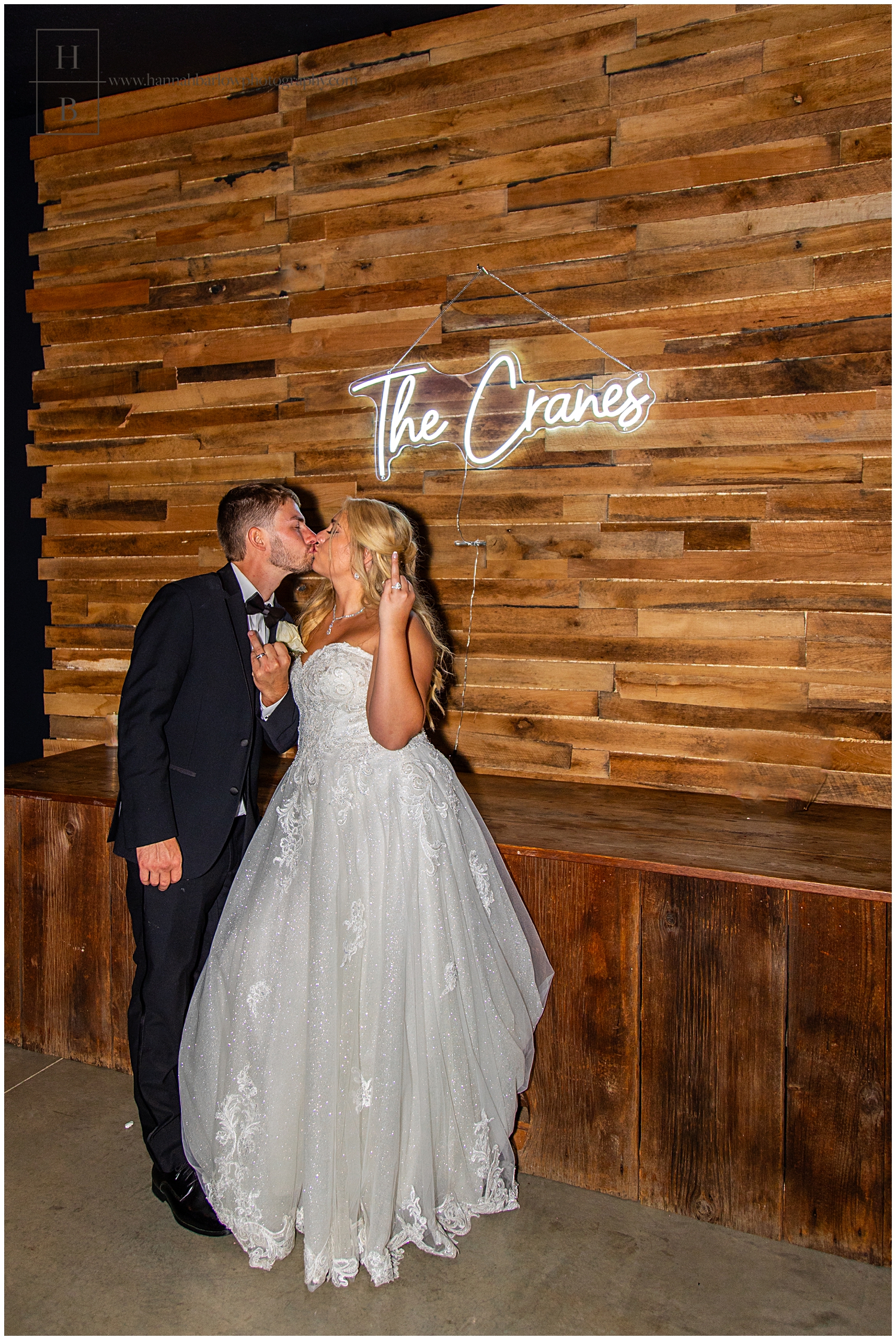 Couple poses in front of last name sign and shows off ring fingers