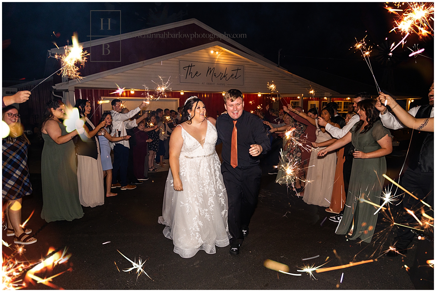 Bride and groom walk out while guests hold sparklers.