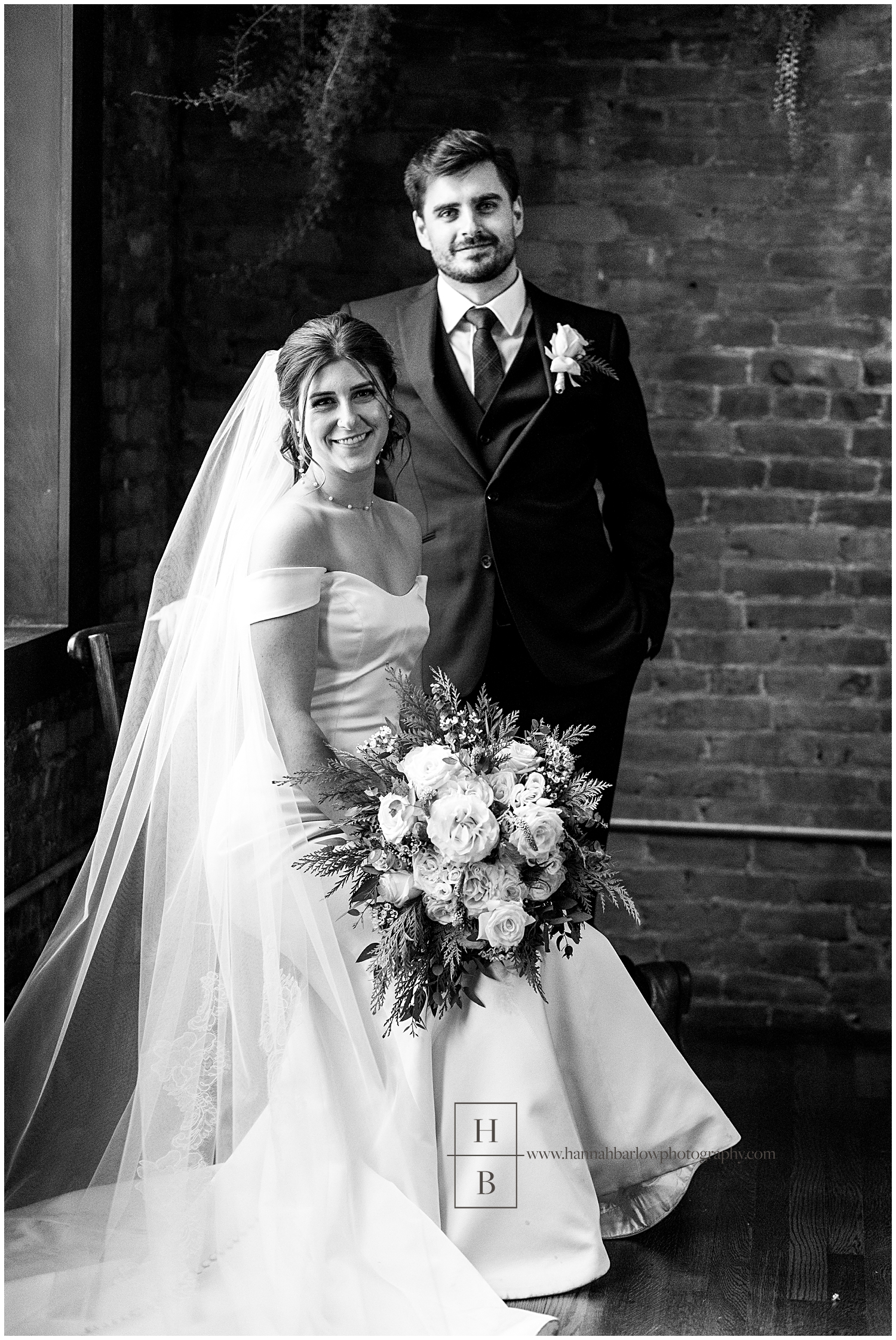 Bride sits on chair and poses with standing groom for wedding photo