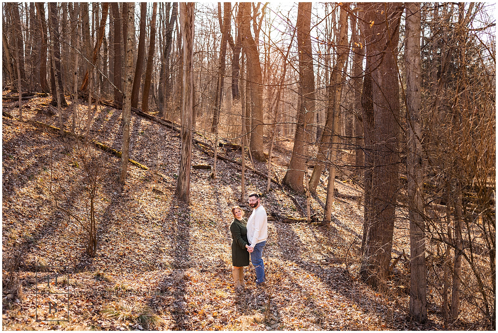 Golden sunlight comes through trees while couple poses for engagement photos