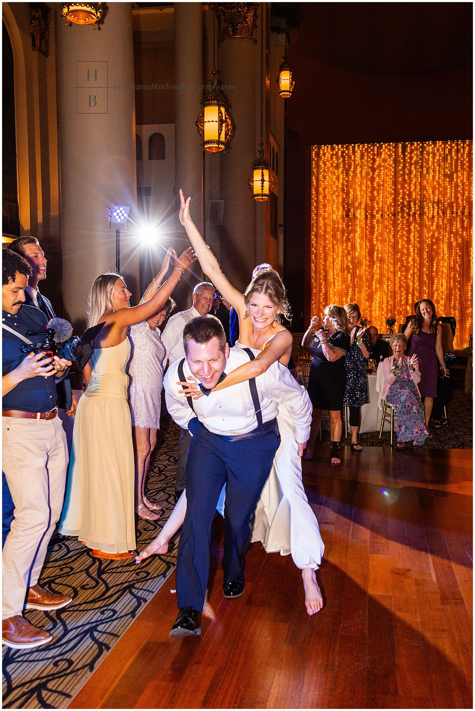 groom carries bride on his back on dance floor