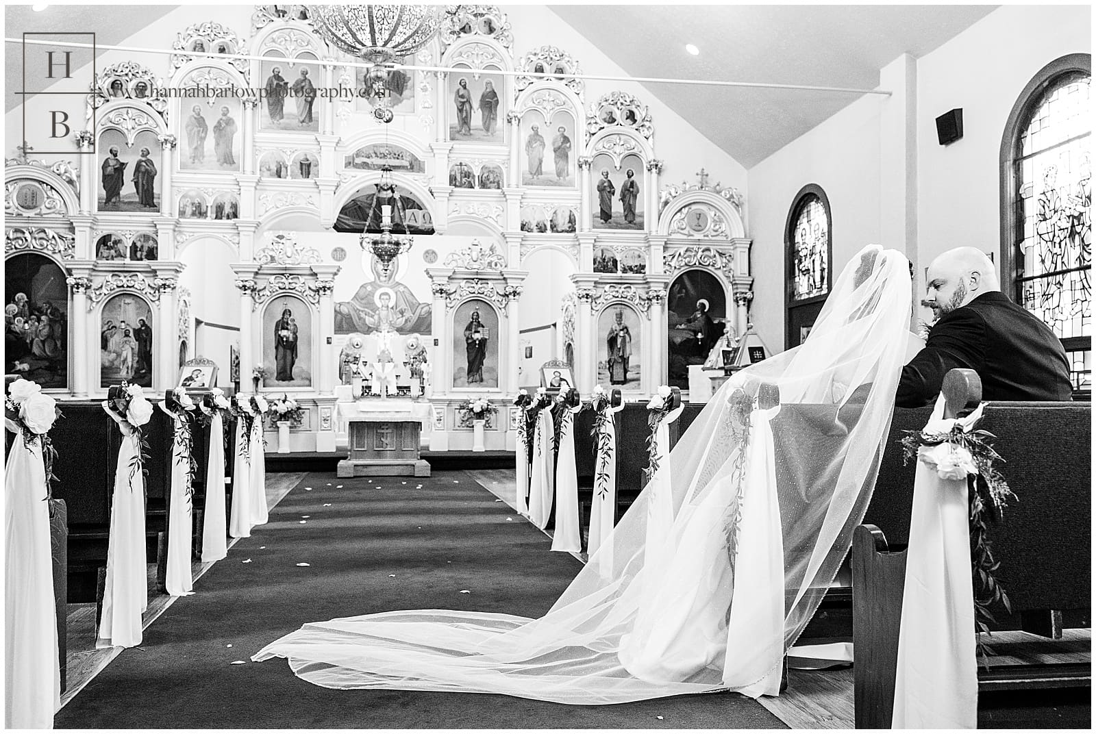 Black and white photo of bride and groom sitting in pew inside church