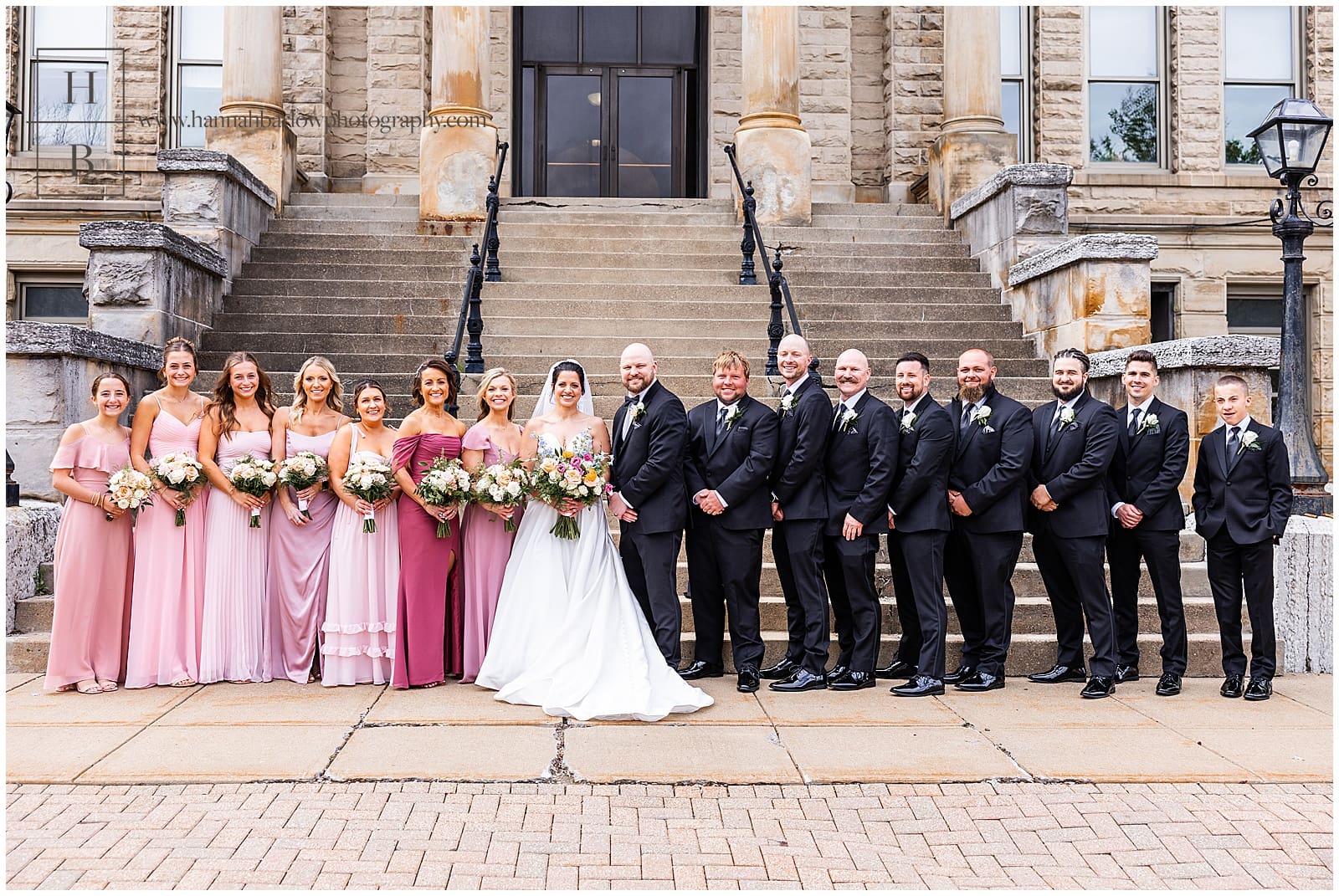 Wedding party in black and pink pose with bride and groom