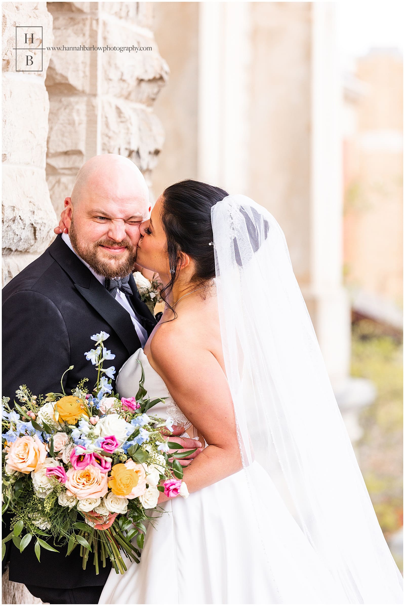 Groom scrunches his face in funny moment as bride kisses his cheek
