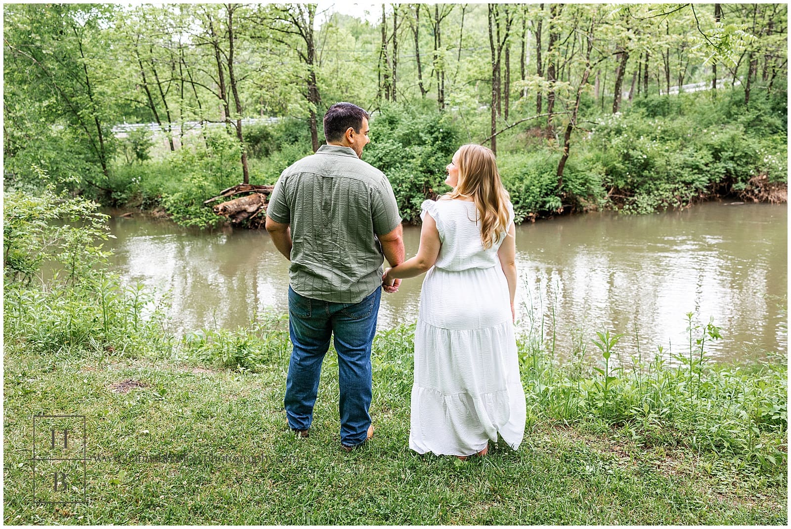couple holds hands and looks out at creek