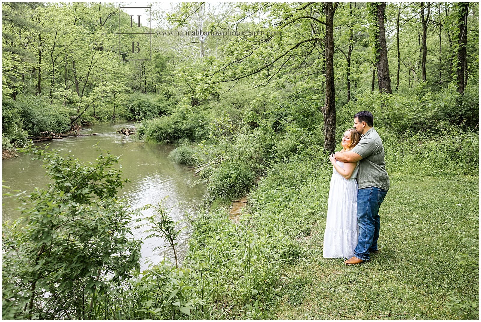 man embraces woman from behind and looks out at creek
